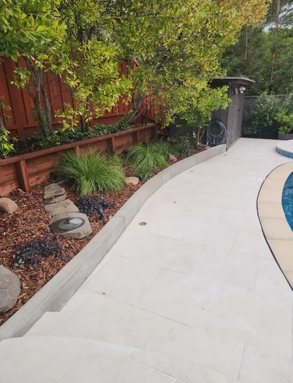 Lush garden bed with raised plantings beside paver patio